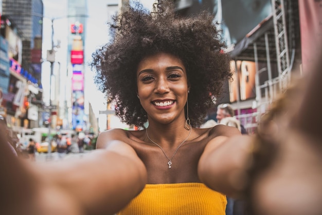Ritratto di una giovane donna felice con i capelli afro che si fa un selfie in una strada della città