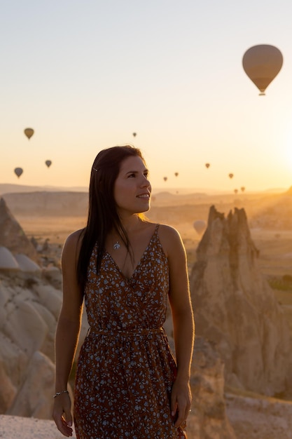 Ritratto di una giovane donna felice con la silhouette di mongolfiere che volano all'alba sullo sfondo