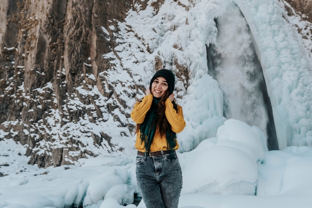 Ritratto di una giovane donna felice presso la cascata. Vai alla cascata in inverno.