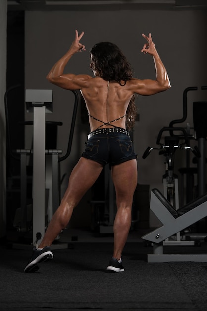 Ritratto di una giovane donna fisicamente in forma che mostra il suo corpo ben allenato modello di fitness bodybuilder atletico muscolare in posa dopo gli esercizi