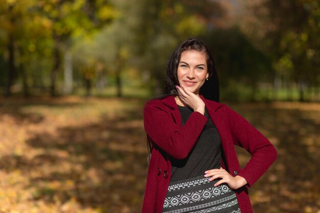 Ritratto di una giovane donna gioiosa che gode nel parco autunnale.