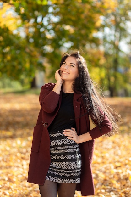 Ritratto di una giovane donna gioiosa che gode nel parco autunnale.