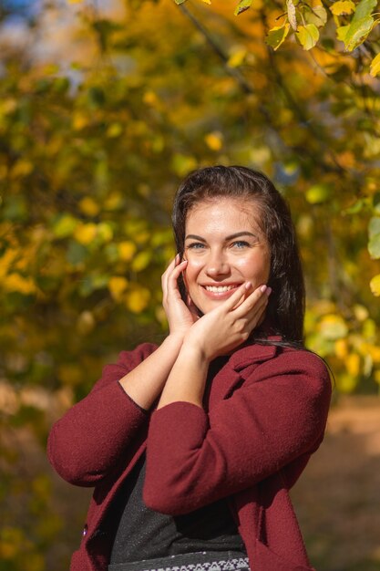 Ritratto di una giovane donna gioiosa che gode nel parco autunnale.