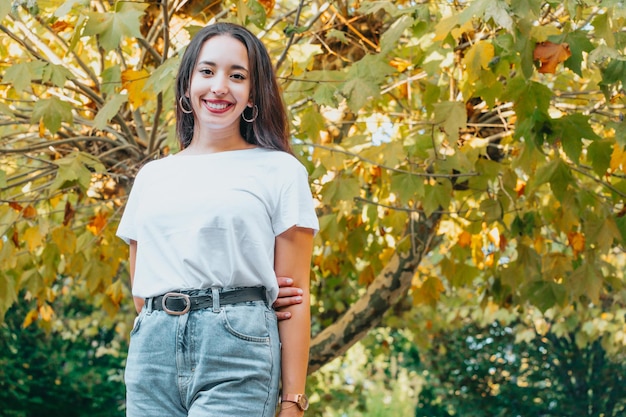 Ritratto di una giovane donna in camicia bianca che indica accanto a lei in una foresta autunnale durante l'autunno. Concetto di stagione, spazio vuoto, copia spazio, distogliendo lo sguardo dalla fotocamera