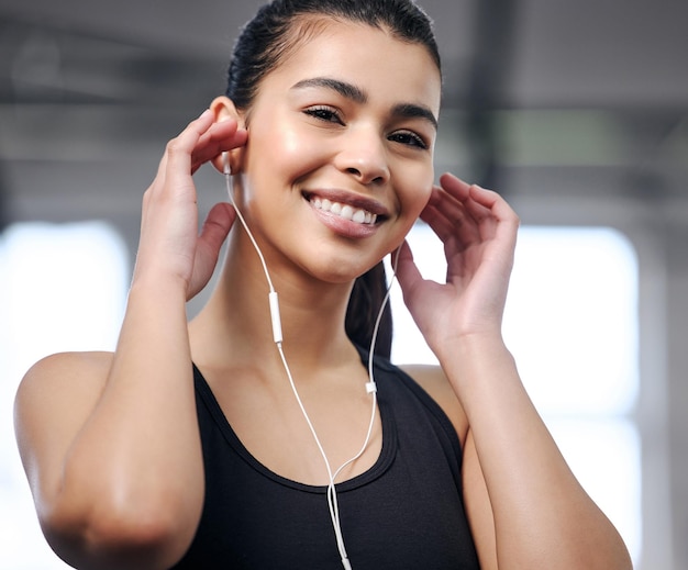 Ritratto di una giovane donna in forma che utilizza gli auricolari in palestra