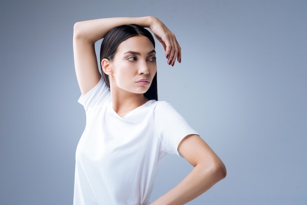 ritratto di una giovane donna in maglietta bianca in posa contro un muro grigio