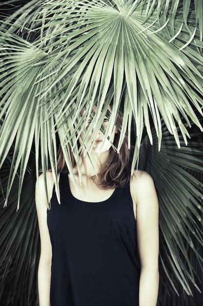 Ritratto di una giovane donna in piedi vicino a una palma