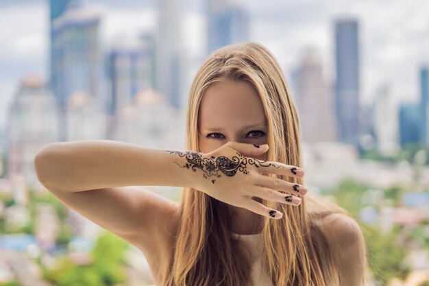 Ritratto di una giovane donna in stile casual con mehendi sullo sfondo di una grande città