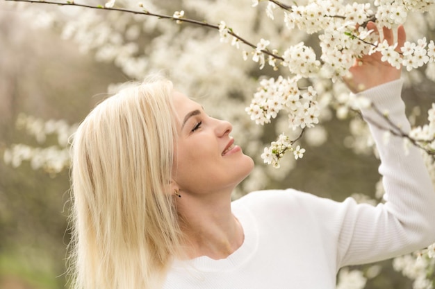 Ritratto di una giovane donna in un frutteto in fiore. Donna bionda