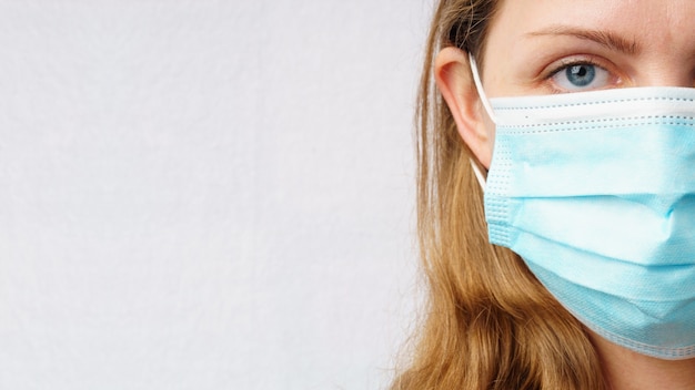 Ritratto di una giovane donna in una mascherina medica monouso protettiva.