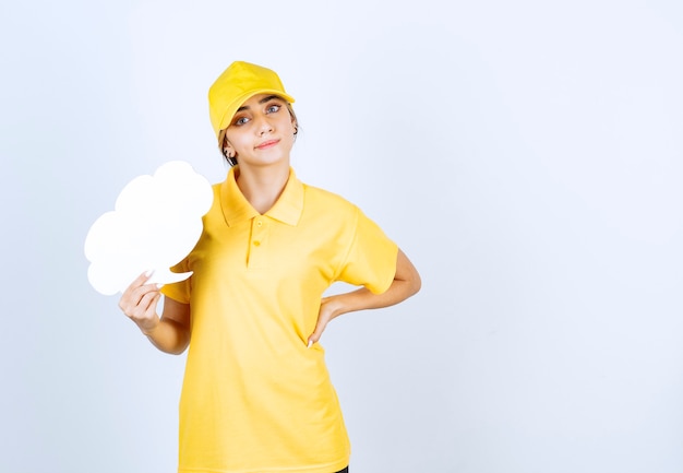 Ritratto di una giovane donna in uniforme gialla che tiene una nuvola bianca vuota di nuvoletta.