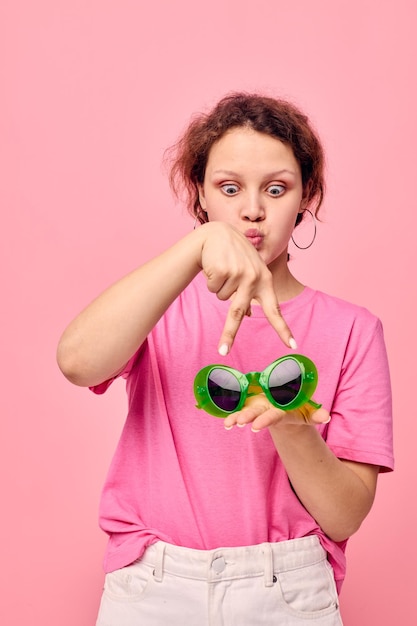 Ritratto di una giovane donna moda occhiali verdi rosa tshirt decorazione in posa