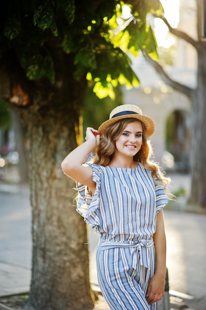 Ritratto di una giovane donna molto attraente in generale a strisce in posa con il suo cappello su un marciapiede in una città