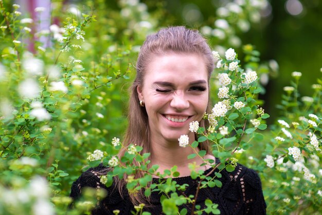 Ritratto di una giovane donna sorridente che fa l'occhiolino in mezzo alle piante