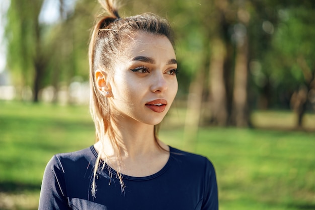 Ritratto di una giovane donna sorridente che indossa abbigliamento sportivo nel parco mattutino