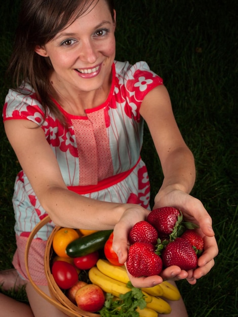 Ritratto di una giovane donna sorridente che tiene le verdure nel carrello.