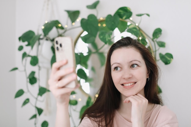 Ritratto di una giovane donna sorridente che tiene smartphone facendo selfie o chat video