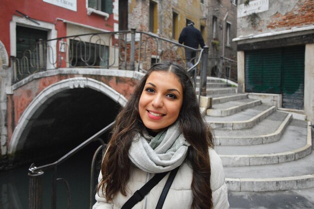 Ritratto di una giovane donna sorridente con i capelli lunghi contro il ponte sul canale dagli edifici