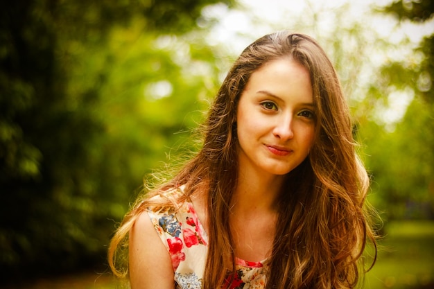 Ritratto di una giovane donna sorridente in piedi contro gli alberi