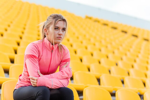 Ritratto di una giovane donna sportiva che riposa allo stadio