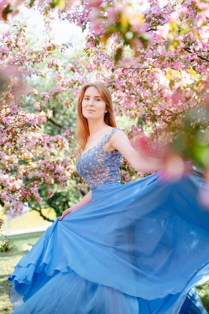 ritratto di una giovane donna su uno sfondo di mele in fiore e ciliegi in primavera