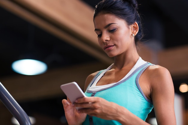 Ritratto di una giovane donna utilizza lo smartphone in una palestra per il fitness