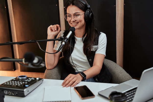 Ritratto di una giovane e attraente conduttrice radiofonica che sembra allegra mentre parla nel microfono