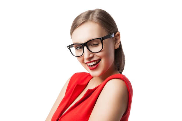 Ritratto di una giovane e bella donna che fa l'occhiolino alla telecamera mentre indossa un abito rosso e occhiali