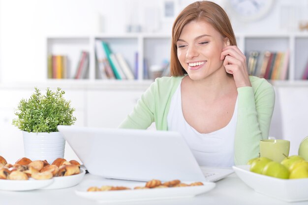 Ritratto di una giovane e bella donna che utilizza computer portatile all'interno