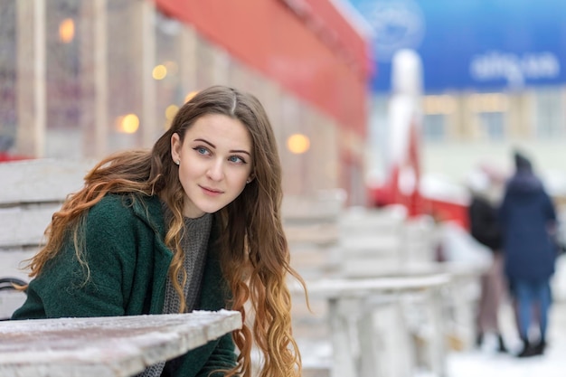 ritratto di una giovane e bella donna dietro un tavolo di legno innevato su una strada cittadina