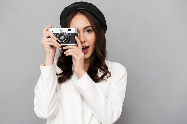 Ritratto di una giovane e bella donna vestita in giacca su sfondo grigio, scattare una foto con la macchina fotografica