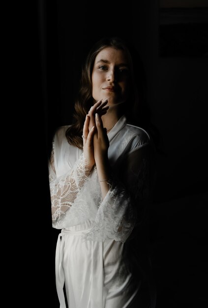 Ritratto di una giovane e bella sposa durante i preparativi mattutini il giorno del matrimonio. bella ragazza tiene un velo sulla sua testa. mattina del matrimonio della sposa.