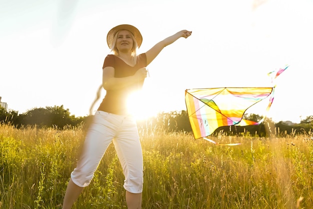 Ritratto di una giovane e spensierata donna che lancia un aquilone sul greenfield. Concetto di stile di vita attivo in natura