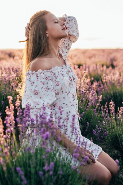 Ritratto di una giovane ragazza bionda in un campo di lavanda in estate al tramonto