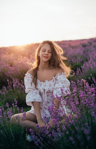 Ritratto di una giovane ragazza bionda in un campo di lavanda in estate al tramonto