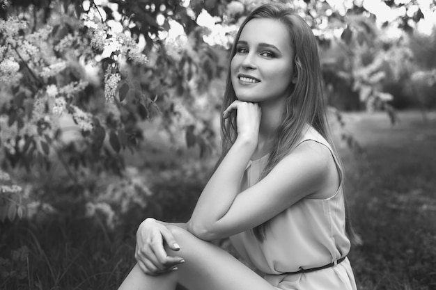 Ritratto di una giovane ragazza bionda in un vestito blu. alberi in fiori.