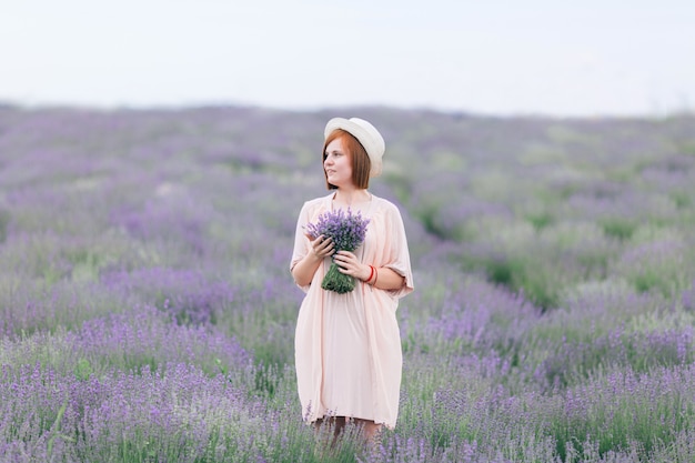 Ritratto di una giovane ragazza carina in un abito rosa in un campo di lavanda