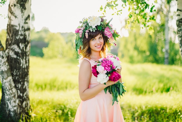 Ritratto di una giovane ragazza caucasica con una corona in testa e un bouquet di peonie