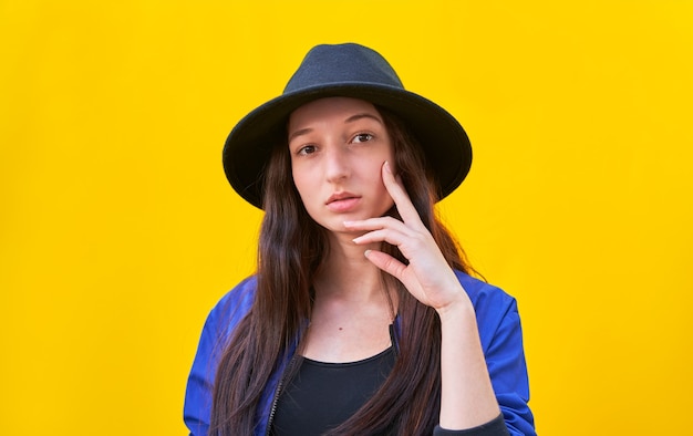 Ritratto di una giovane ragazza caucasica in cappello nero e giacca blu, cosegnare il viso