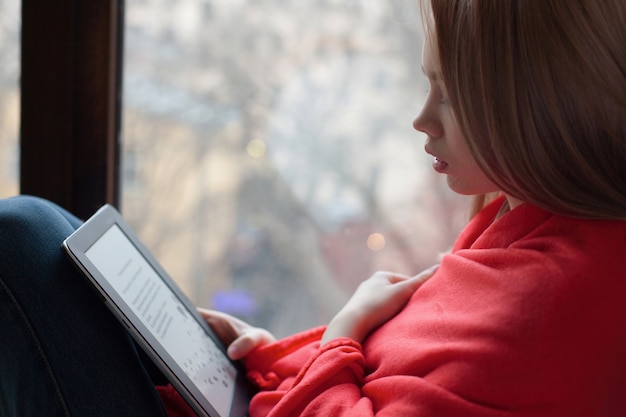 Ritratto di una giovane ragazza che legge un e-book.