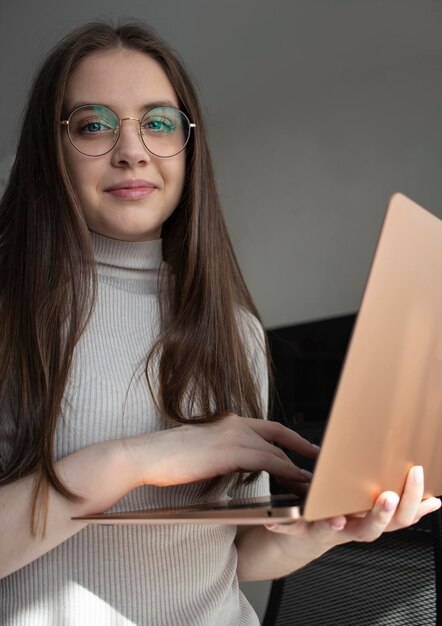 ritratto di una giovane ragazza con gli occhiali in possesso di un computer portatile