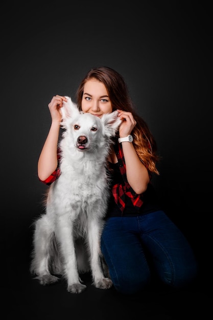 Ritratto di una giovane ragazza con il suo cane in studio su sfondo nero