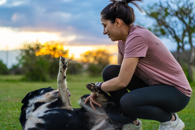 Ritratto di una giovane ragazza felice che accarezza il suo cane sdraiato sull'erba