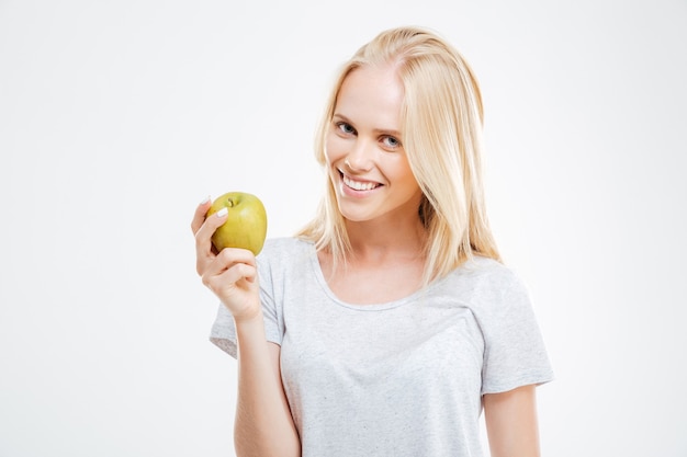 Ritratto di una giovane ragazza felice che tiene mela verde isolata su un muro bianco