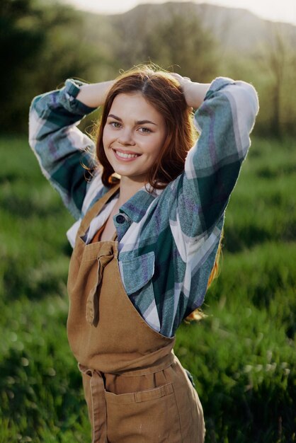 Ritratto di una giovane ragazza in un giorno d'estate sotto i raggi del sole al tramonto con un bel sorriso vestito da contadino e giardiniere