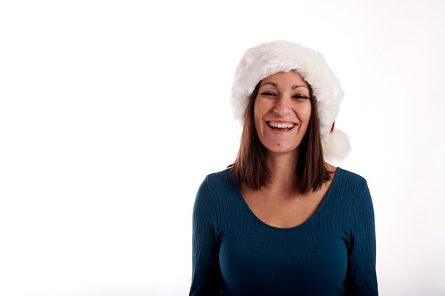 Ritratto di una giovane ragazza sorridente con un cappello di Babbo Natale su uno sfondo bianco.