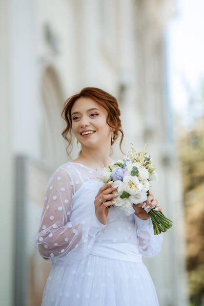 Ritratto di una giovane ragazza sposa in un abito leggero in un ambiente urbano