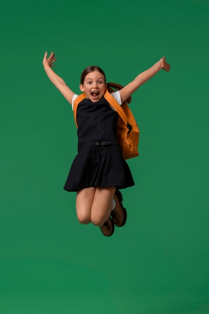 Ritratto di una giovane studentessa in uniforme scolastica che salta a mezz'aria