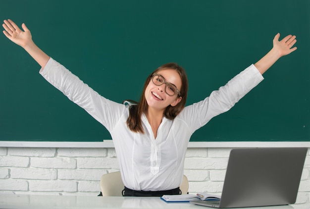 Ritratto di una giovane studentessa stupita eccitata con le mani alzate nell'aula scolastica