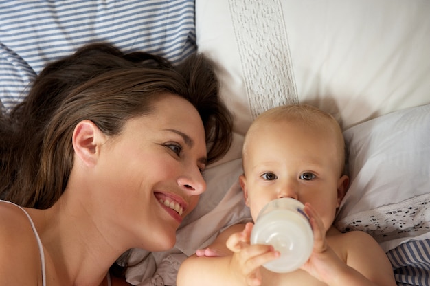 Ritratto di una madre felice con bambino carino bere dalla bottiglia